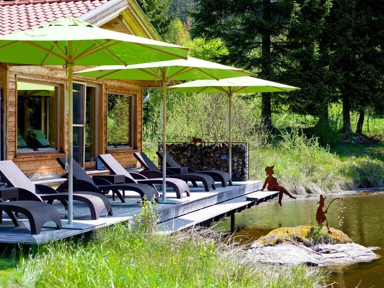 Auf der Terrasse eines Seehauses liegen gemütliche Liegestühle zum Entspannen mit Blick auf den See.