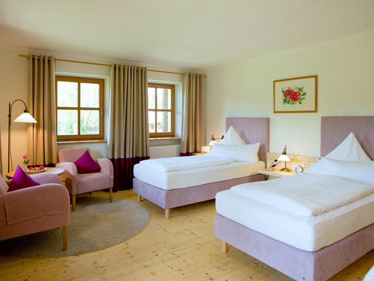 Zwei gemütliche Betten und mehrere Sessel füllen das komfortable Schlafzimmer der Schönheitsfarm Fohlenhof.